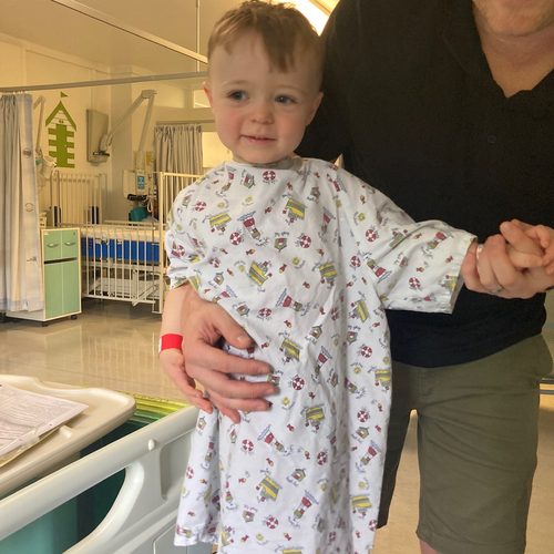 Freddie in his hospital gown, holding his dad's hand