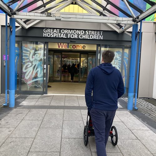 Dad pushing Freddie's stroller toward Great Ormond Street Hospital entrance