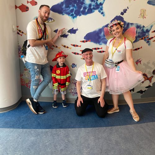 Freddie in a fireman costume with volunteers in an underwater-themed room