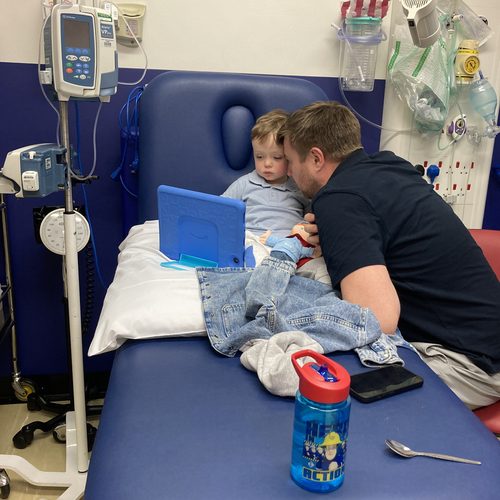 Freddie and his dad looking at a tablet together in hospital